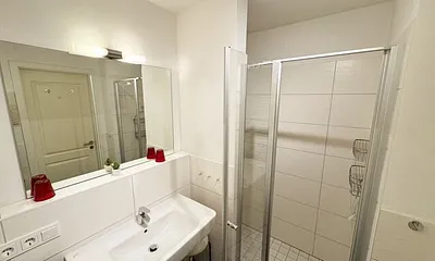 Badezimmer mit ebenerdiger Glasdusche, Fön, Waschbecken, WC und Handtuchtrockner