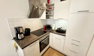 integrierte helle Küchenzeile mit Backofen, Ceranfeld, Spülmaschine, Kühlschrank, Nespresso Maschine, Kaffeemaschine, Toaster, Wasserkocher und anderen praktischen Helfern