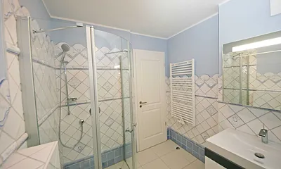 Badezimmer mit ebenerdiger Echtglasdusche, WC, Handtuchtrockner sowie Badmöbel