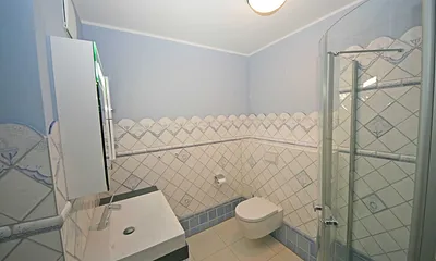 Badezimmer mit ebenerdiger Echtglasdusche, WC, Handtuchtrockner sowie Badmöbel