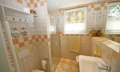 Badezimmer mit ebenerdiger Dusche, WC, großem Waschbecken, Fön, großzügigem Wandspiegel und ein Bidet
