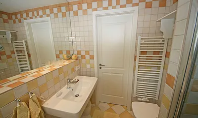 Badezimmer mit ebenerdiger Dusche, WC, großem Waschbecken, Fön, großzügigem Wandspiegel und ein Bidet