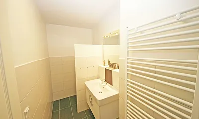 Badezimmer mit ebenerdiger Dusche, Waschtisch, WC, beheizbarer Handtuchtrockner und Fön