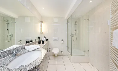 Hier ein Blick in das große Bad mit Echtglasdusche, Fön und WC.