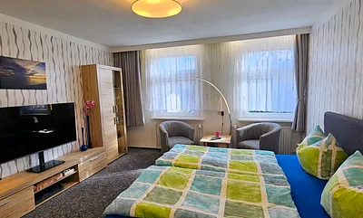 Schlafzimmer mit Doppelbett (180×200cm),Anbauwand mit TV, Tisch und 2 Clubsessel ,Leselampe, Verducklungsvorhang 