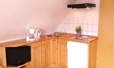 Küchenzeile (2-Platten-Herd. Kaffeemaschine, Wasserkocher, Toaster) mit Entertainmentbereich (Flachbild-TV, Bücherecke)