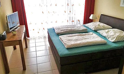 Schlafzimmer mit Doppelbett-Boxspringmatratzen und TV