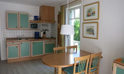 In den Wohnbereich harmonisch integriert ist eine komplett eingerichtete Küchenzeile. Durch das raumhohe Seitenfenster schaut man ins Grüne u. in den Frühjahrs- und Wintermonaten sogar auf das Meer.