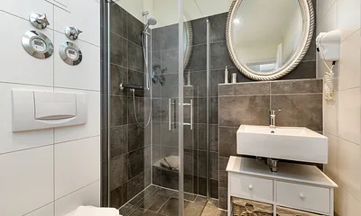 Das schicke Bad bietet Ihnen eine bodengleiche Echtglasdusche, Fön, beleucheten Kosmetikspiegel und WC.