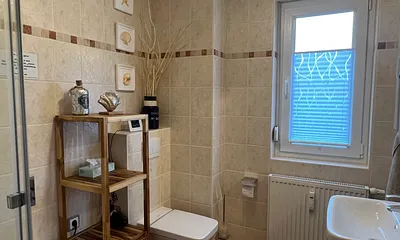 Im großen raumhoch gefliesten Bad befinden sich das WC, Dusche und der Waschtisch. Ein Fön befindet sich im Badschrank. 