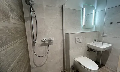 Bad- Blick von der Dusche, in Marmor-Beton-/ Holzoptik gefliest 