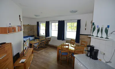 Wohnzimmer mit großem Esstisch, zwei Relaxsesseln und Couch