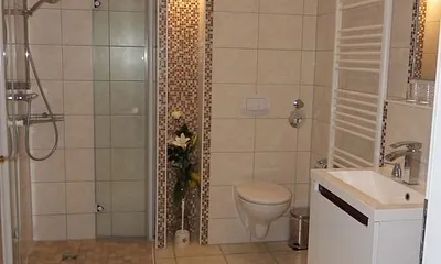 Bad mit Fön, Duschhocker, Schrank, Tageslicht und großen Spiegeln. Hintere Badansicht