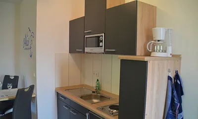 Küchenzeile mit Mikrowelle, Kaffeemaschine, Wasserkocher, Toaster.