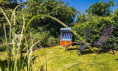 Eingezäunter Garten mit Strandkorb und Sonnenliegen