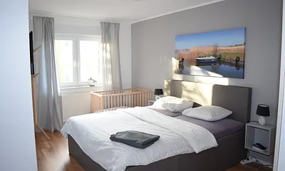 Schlafzimmer 1 mit Babybett und TV