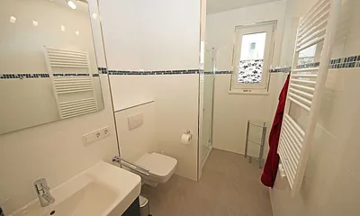 komfortables Badezimmer mit ebenerdiger Dusche, Waschtisch, Handtuchheizkörper, WC und Fön