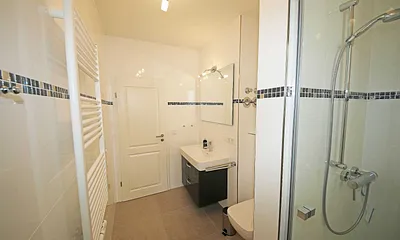 komfortables Badezimmer mit ebenerdiger Dusche, Waschtisch, Handtuchheizkörper, WC und Fön