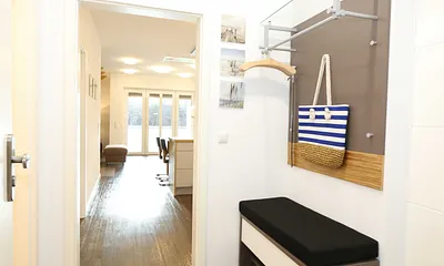 heller Flur mit Garderobe, Sitzgelegenheit und bodentiefem Spiegel