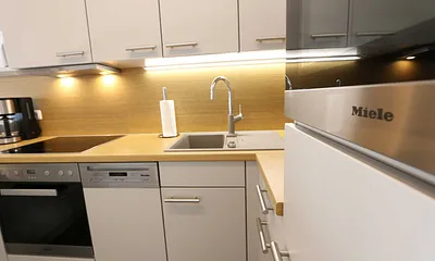 Küchenzeile mit Mikrowelle, Backofen, Induktionskochfeld, Geschirrspüler, Kaffeemaschine, Pad-Maschine (Senseo), Wasserkocher, Eierkocher, Toaster, Handmixer und Kühlschrank mit Gefrierfach 