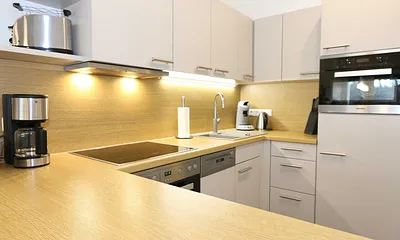 Küchenzeile mit Mikrowelle, Backofen, Induktionskochfeld, Geschirrspüler, Kaffeemaschine, Pad-Maschine (Senseo), Wasserkocher, Eierkocher, Toaster, Handmixer und Kühlschrank mit Gefrierfach 