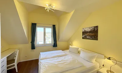 Schlafzimmer mit Doppelbett (1,80 m x 2,00 m mit Komforthöhe), Nachttischablagen, Kleiderschrank, Schreibtisch und Flachbild-TV