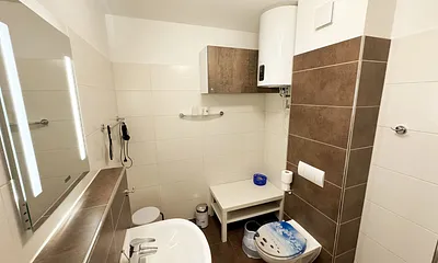 Badezimmer mit Dusche, WC, Kosmetikspiegel, Fön, Waschbecken und Handtuchwärmeheizkörper