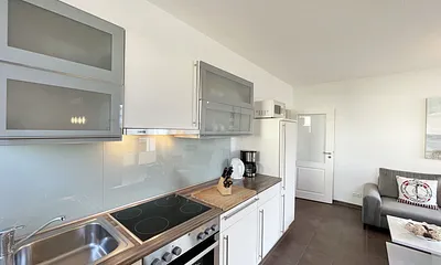 Küchenzeile mit Cerankochfeld, Backofen, Dunstabzugshaube, Kühlschrank mit Gefrierfach, Spülmaschine, Kaffeemaschine, Mikrowelle, Wasserkocher, Toaster und diverse Küchenutensilien