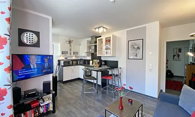 Wohnzimmer mit TV und Blick zur Küchenzeile