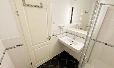 Badezimmer mit ebenerdiger Glasdusche, WC, Fön und Handtuchheizkörper