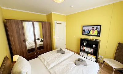 komfortables Schlafzimmer mit Doppelbett (1,80 m x 2,00 m), hochwertigen Matratzen, verstellbaren Lattenrosten, 2 Nachttischlampen, Flachbild-TV und Kleiderschrank