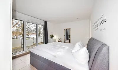 Schlafzimmer mit Boxspringbett und Zugang zum Balkon