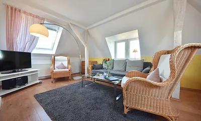 Wohnbereich mit Couch und gemütlichen Korbsesseln