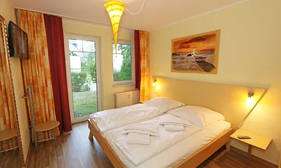 Schlafzimmer mit Doppelbett (1,80 m x 1,90 m), Nachttischkonsolen, Smart-TV, geräumiger Kleiderschrank, großer Wandspiegel und einem Herrendiener mit Sitzmöglichkeit
