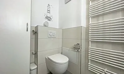 Badezimmer mit Dusche, WC, Kosmetikspiegel, Waschtisch und einem mobilen Wäscheständer