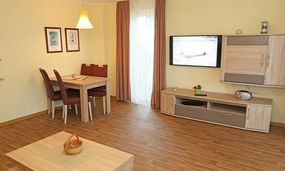 Wohnzimmer mit Couch (Aufbettung für 3./4. Person, 1,50 m  x 2,00 m), Couchtisch, Leselampe, Smart-TV, Radio mit CD-Player
