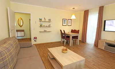 Wohnzimmer mit Couch (Aufbettung für 3./4. Person, 1,50 m  x 2,00 m), Couchtisch, Leselampe, Smart-TV, Radio mit CD-Player