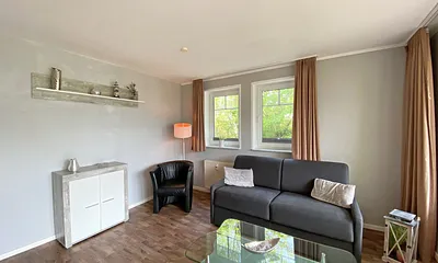 Wohnzimmer mit Schlafcouch (Aufbettung 3./4. Person, 1,60 m x 2,00 m), Sessel, TV sowie Blu-Ray-Player