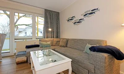 Wohnbereich mit einer gemütlichen Couch (Aufbettung für 3. und 4. Person, Liegefläche 1,60 m x 2,00 m), Couchtisch, gemütlichen Ohrensessel, Leselampe, Lowboard mit Smart-TV und Blu Ray-Player