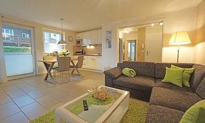 Wohnzimmer mit Esstisch und vollausgestatteter Küchenzeile