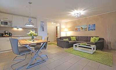 Wohnzimmer mit Esstisch und vollausgestatteter Küchenzeile