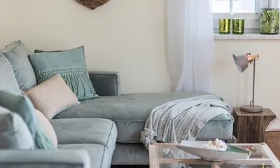 Wohnbereich mit Couch, Couchtisch, Sessel, Leselampe, Sideboard, Smart-TV, DAB Radio, Blu Ray Player sowie durchgängige Fensterfront mit fantastischem Panorama- und Meerblick