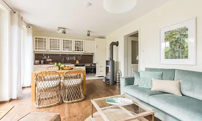 Wohnbereich mit Couch, Couchtisch, Sessel, Leselampe, Sideboard, Smart-TV, DAB Radio, Blu Ray Player sowie durchgängige Fensterfront mit fantastischem Panorama- und Meerblick