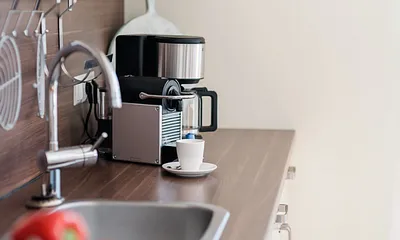 Küchenzeile mit Cerankochfeld, Dunstabzugshaube, Backofen, Geschirrspüler, Kühlschrank mit Eisfach, Kaffeemaschine, Wasserkocher, Toaster und diversen Küchenutensilien