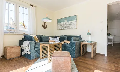 Wohnbereich mit Couch, Couchtisch, Leselampe, Sideboard, Smart-TV, DAB Radio, Blu Ray Player sowie durchgängige Fensterfront mit fantastischen Panorama- und Meerblick