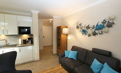 Wohnzimmer mit gemütlicher Couch, Couchtisch, Ohrensesel mit Hocker, Leselampe, Smart-TV, Radio mit CD-Player und Bluetooth/USB sowie eine Vitrine