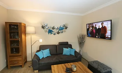 Wohnzimmer mit gemütlicher Couch, Couchtisch, Ohrensesel mit Hocker, Leselampe, Smart-TV, Radio mit CD-Player und Bluetooth/USB sowie eine Vitrine