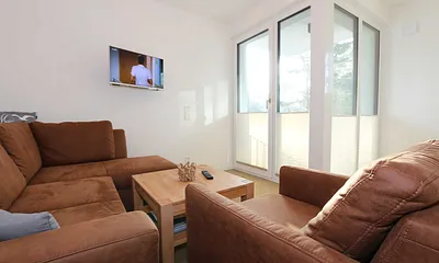 Wohnbereich mit Eckcouch, Couchtisch, Sessel, Vitrine, Smart-TV mit integriertem Radio, USB-Anschluss und Bluetooth