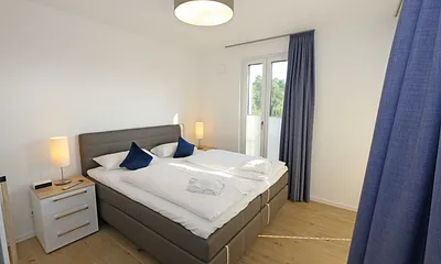 Schlafzimmer mit Boxspringbett (1,80 m x 2,00 m) in Komforthöhe, Nachttischablagen mit Wandleuchten, großzügiger Kleiderschrank und Smart-TV