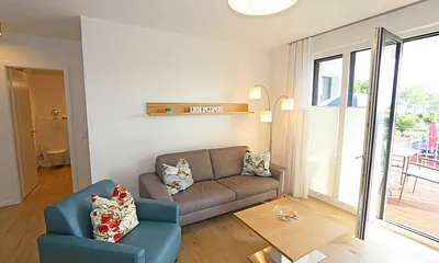 offener Wohn-/ Küchenbereich mit Couchtisch, Sessel, Stehlampe, Sideboard, bequemer Ledercouch, Smart-TV von Loewe mit Blu-Ray-Player und Musik-CD`s